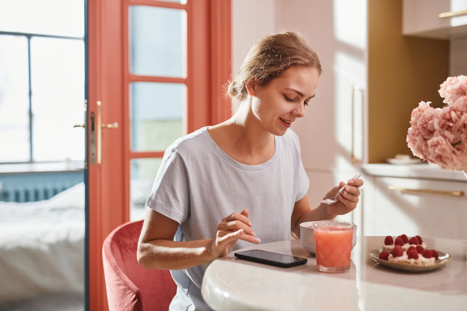 A woman enjoying breakfast at a sunlit table.