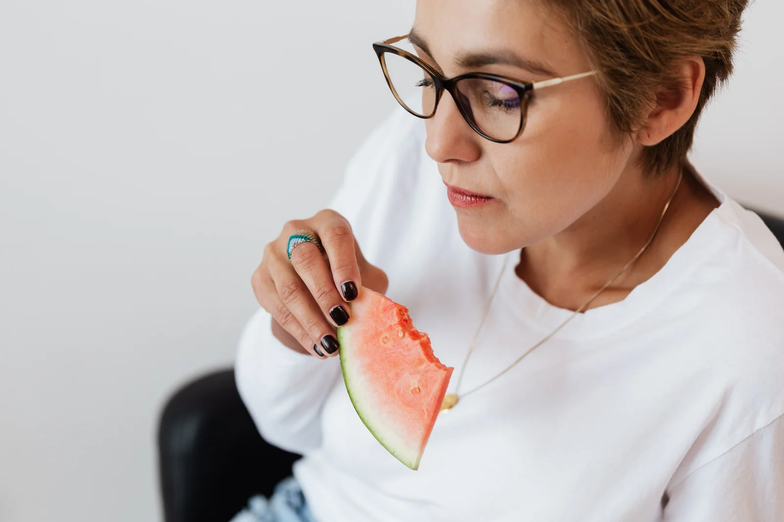 A woman takes a quiet break to eat a slice of watermelon.