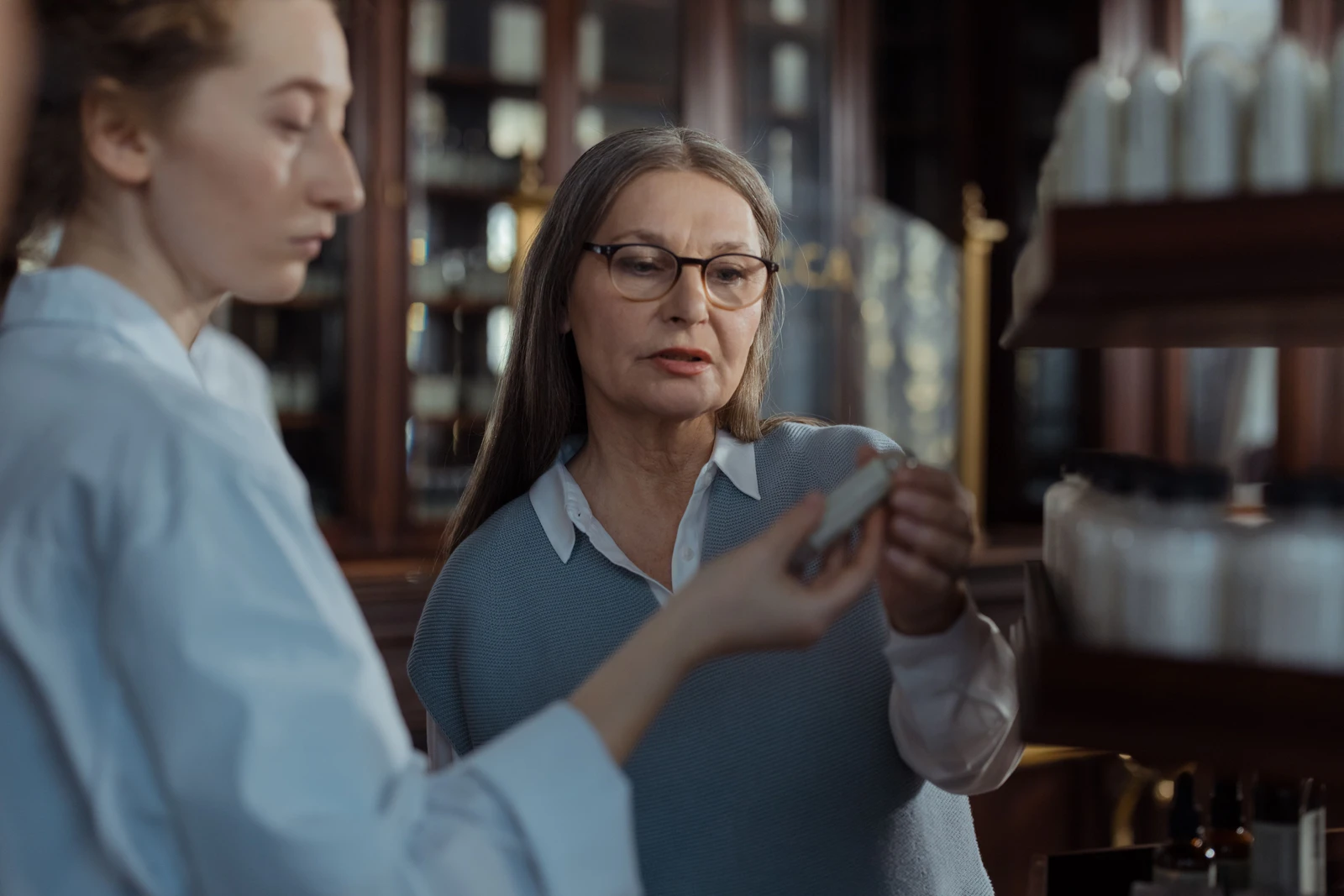 An adult and a pharmacist examine a product package together.
