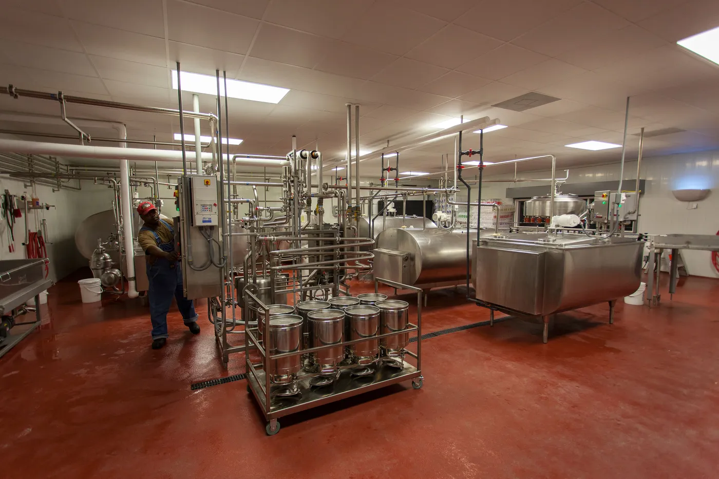 An operator among stainless-steel tanks and pipes in a milk-processing facility.