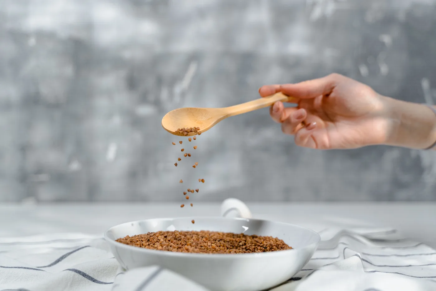 Seeds being spooned into a bowl as a visual for dried grains
